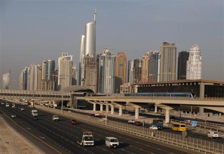 Buildings are seen under construction, ahead of rush hour traffic as a Dubai Metro train arrives at a station in Dubai