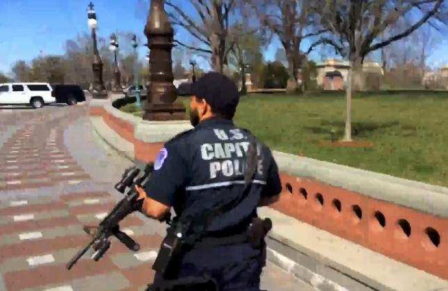 A U.S. Capitol police officer runs towards the entrance to the U.S. Capitol Visitors Center with his weapon in this video frame grab after a shooting in Washington