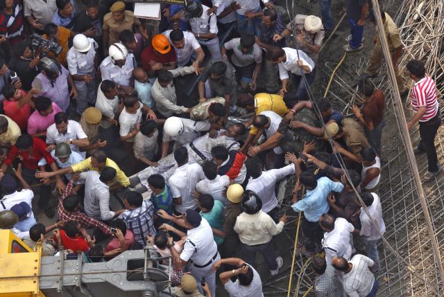 Rescue members carry a policeman after he was rescued at the site of an under-construction flyover that collapsed in Kolkata
