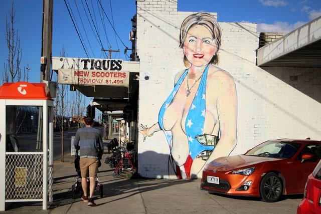 A mural painted by street artist Lushsux, bearing the image of U.S. Democratic Party nominee for President Hillary Clinton wearing a stars-and-stripes themed swimsuit stuffed with cash on the wall of a business in the Melbourne suburb of Footscray - THEWILL NEWS MEDIA A mural painted by street artist Lushsux, bearing the image of U.S. Democratic Party nominee for President Hillary Clinton wearing a stars-and-stripes themed swimsuit stuffed with cash on the wall of a business in the Melbourne suburb of Footscray, Australia, July 31, 2016. REUTERS/Jarni Blakkarly