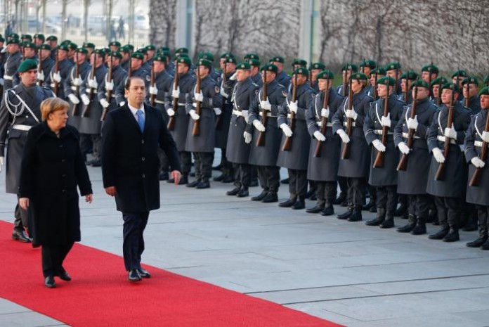 German Chancellor Merkel and Tunisian Prime Minister Chahed review the guard of honour at the Chancellery in Berlin
