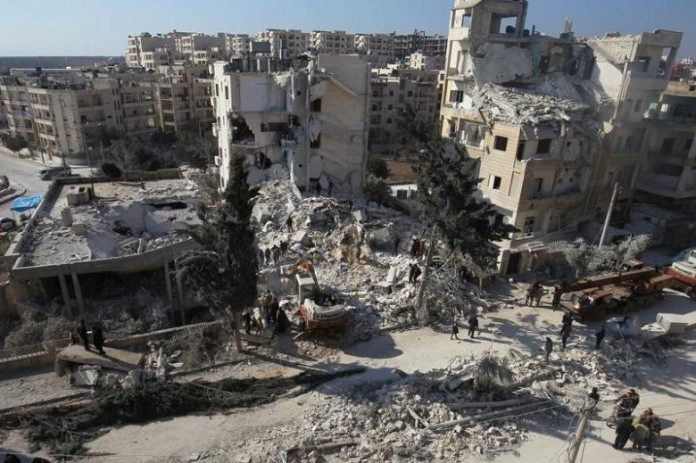 FILE PHOTO: People inspect the damage at a site hit by airstrikes in the rebel-held city of Idlib