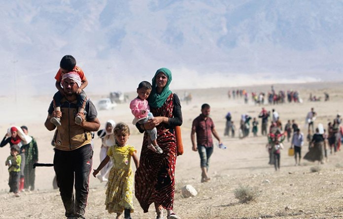 Displaced people from the minority Yazidi sect, fleeing violence from forces loyal to the Islamic State in Sinjar town, walk towards the Syrian border, on the outskirts of Sinjar mountain, near the Syrian border town of Elierbeh of Al-Hasakah Governorate