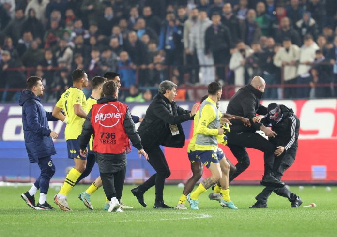 Super Lig - Trabzonspor v Fenerbahce Soccer Football - Super Lig - Trabzonspor v Fenerbahce - Papara Park, Trabzon, Turkey - March 17, 2024 A Trabzonspor fan invades the pitch and clashes with Fenerbahce players and security staff after the match. REUTERS/Depo Photos