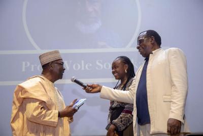 Gen. Gowon (left) presenting Prof. Wole Soyinka’s plaque/ award to his secretary, Lola Ayoola, while the M.C., Patrick Oke, looks on. Gen. Gowon (left) presenting Prof. Wole Soyinka’s plaque/ award to his secretary, Lola Ayoola, while the M.C., Patrick Oke, looks on.