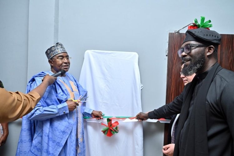 UNODC . - THEWILL NEWS MEDIA Two men in traditional Nigerian attire cut a ribbon to unveil a plaque behind a white-covering panel.