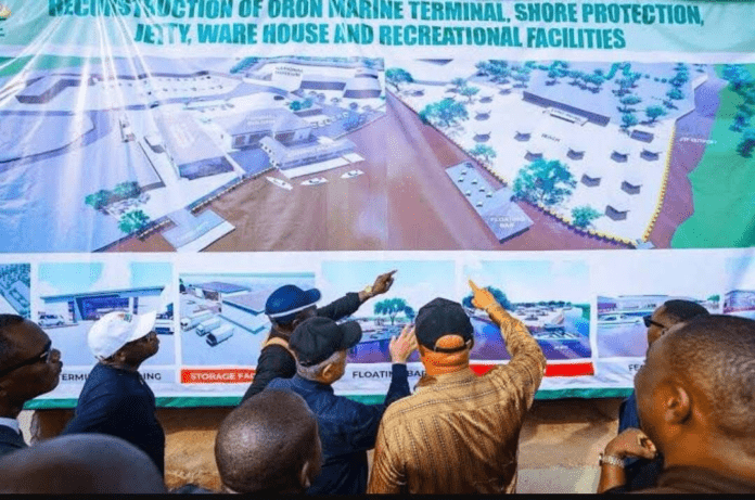 Group of men gathered around a large banner, pointing at a proposed marine terminal and facilities layout with labeled diagrams.