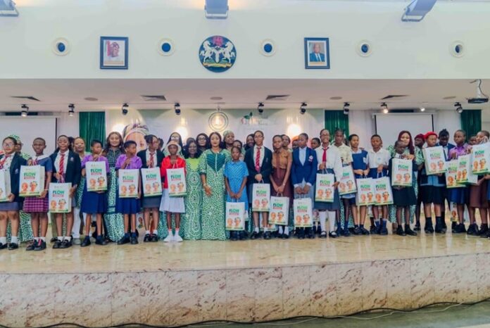 Flow with Confidence” of the Renewed Hope initiative at the Banquet Hall Group of students and a few adults posing on a stage indoors, each student holding a poster or brochure.