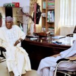 Kano Central: Aspirant Zango Denies Collecting ₦500m Bribe, Says Rumour Baseless Two men in traditional Nigerian attire sit in an office across a polished desk; a guard stands in the background by a filing cabinet and fan.