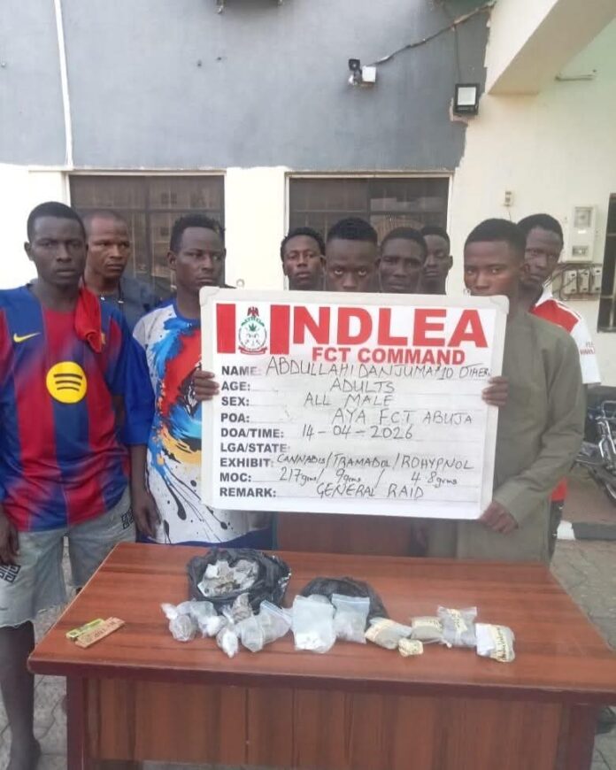 IMG_5627 Group of young men standing behind a sign that reads IN DLEA FCT COMMAND while drugs are displayed on a table in front of them.