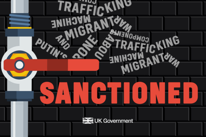 UK Sanctions Graphic showing a large red 'SANCTIONED' caption on a dark brick wall, with a pipe valve and scattered words like 'trafficking' and 'migrant', UK Government logo in the corner.