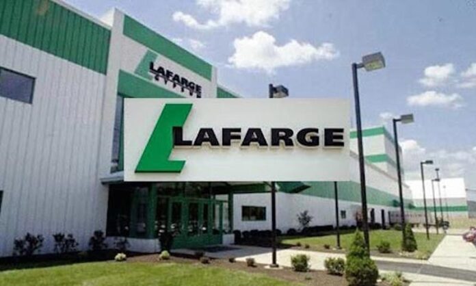 Exterior view of a Lafarge building with a large white sign featuring the green Lafarge logo and name Caution: large corporate sign in front of the entrance.