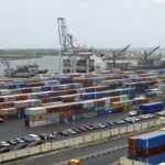 Nine Ships Arrive Lagos Ports with Petroleum Products, Others Busy port scene with rows of colorful shipping containers, cranes, and dockside equipment by the water.