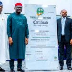MAN’s Dual ISO Certification Positions Nigeria For Global Maritime Relevance – FG Five men in traditional and formal dress pose beside a tall certificate board from the Standards Organisation of Nigeria (SON).