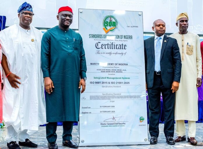 Five men in traditional and formal dress pose beside a tall certificate board from the Standards Organisation of Nigeria (SON).