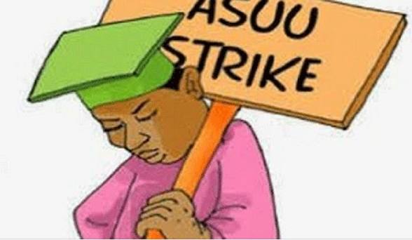 images Cartoon of a student with a green cap carrying a placard labeled 'ASUU STRIKE', signaling a university teachers' strike protest.