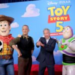 Toy Story 5’ Dominates Box Office With Biggest Worldwide Opening of 2026 Two men posing with life-size Woody and Buzz Lightyear figures on a Toy Story 5 backdrop.