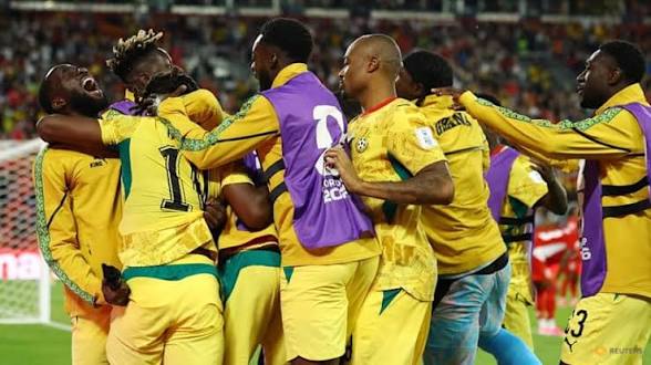 1002299239 Soccer players in yellow uniforms celebrate in a huddle on the field in a stadium, embracing and cheering together.
