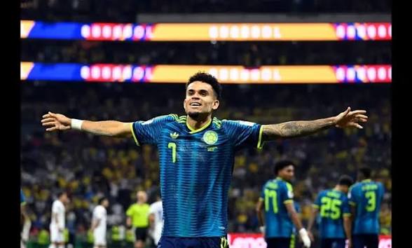 1002299249 Soccer player in a blue jersey with arms outstretched, celebrating on a crowded stadium field.