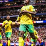 Late Penalty Rescues South Africa In Draw With Czechia Brazilian soccer players celebrate on the field during a match; foreground player wears number 4 in yellow and green.