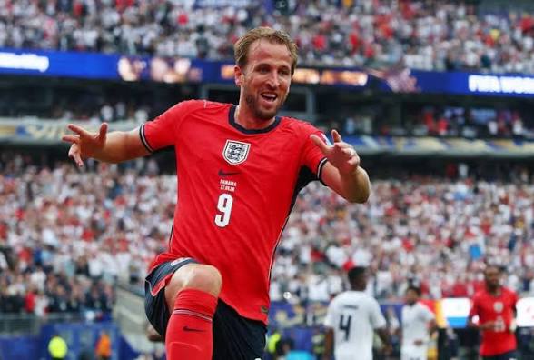 England forward in red jersey with number 9 celebrating a goal on a packed stadium.