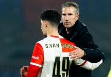 Robin van Persie’s Son Reportedly Picks Morocco Over Netherlands Soccer player S. van Persie wearing a white-red jersey being hugged by a man in a dark jacket on a pitch.