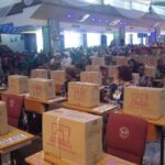 FG Trains South-East Youths On Practical Skills, Empowers 95 For Entrepreneurship Large hall filled with attendees seated at rows of desks; each desk has a cardboard box labeled Butterfly, suggesting held event materials or kits.
