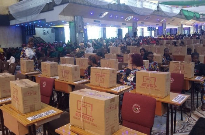 Large hall filled with attendees seated at rows of desks; each desk has a cardboard box labeled Butterfly, suggesting held event materials or kits.