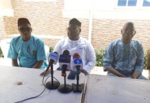 2027: Ogun APC Guber Aspirant Calls For Nullification Of Primary Election Three men sit at a white table outdoors with multiple microphones for a press conference.