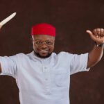 2027: Umuekumenyi Leaders Back Odii As PDP Governorship Candidate Man in a red fez and white traditional outfit, smiling, holds a knife aloft in one hand and a thumbs-up in the other.