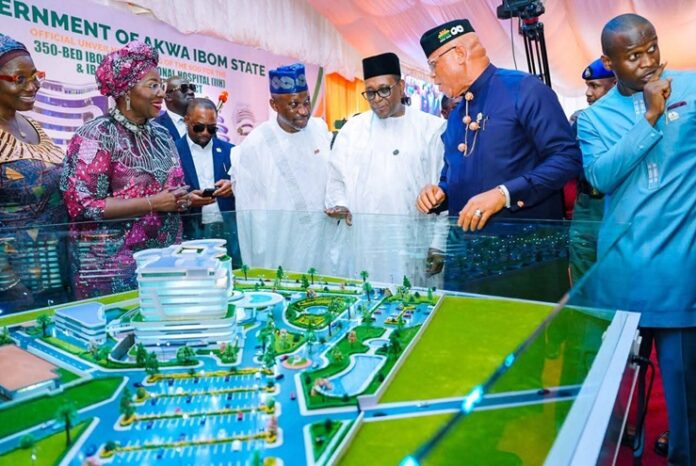 Dignitaries in traditional and formal attire inspect a large government project model with water features at an Akwa Ibom State event.