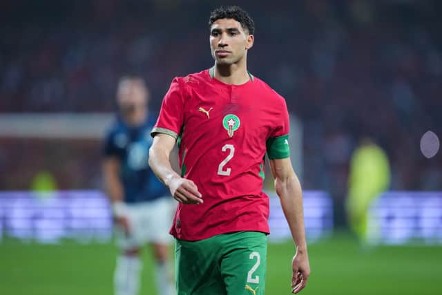 GettyImages-2269536616 (1) Soccer player in red Morocco kit with number 2 and green shorts, wearing captain's armband, on the field.