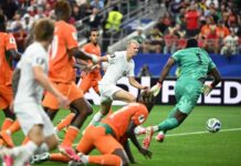 Haaland Fires Norway Into Historic Last 16 With Late Winner Against Ivory Coast White-team attacker shoots toward goal as orange defenders converge and the teal goalkeeper guards the net.