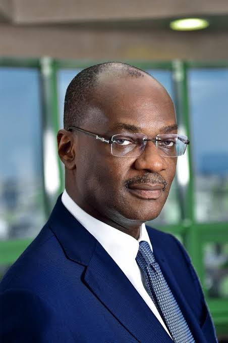 Kunle Elebute Professional portrait of a Black man in a navy suit and glasses, looking at the camera with a neutral expression.