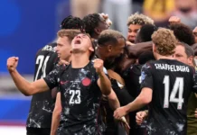 Canada’s Late Strike Breaks South Africa Hearts in Dramatic World Cup Clash Football players in black jerseys celebrate a goal, arms raised in jubilation, numbers 23 and 14 visible (Shaffelburg).