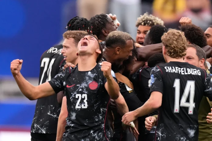 CANADA Football players in black jerseys celebrate a goal, arms raised in jubilation, numbers 23 and 14 visible (Shaffelburg).