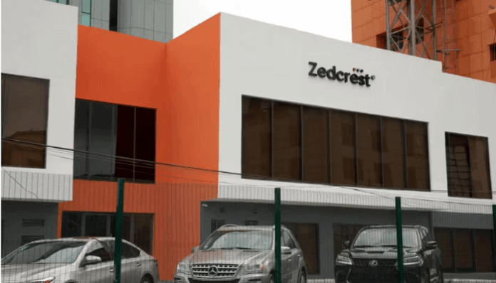 Zedcrest Zedcrest office building with orange and white façade and parked cars in front behind a green fence