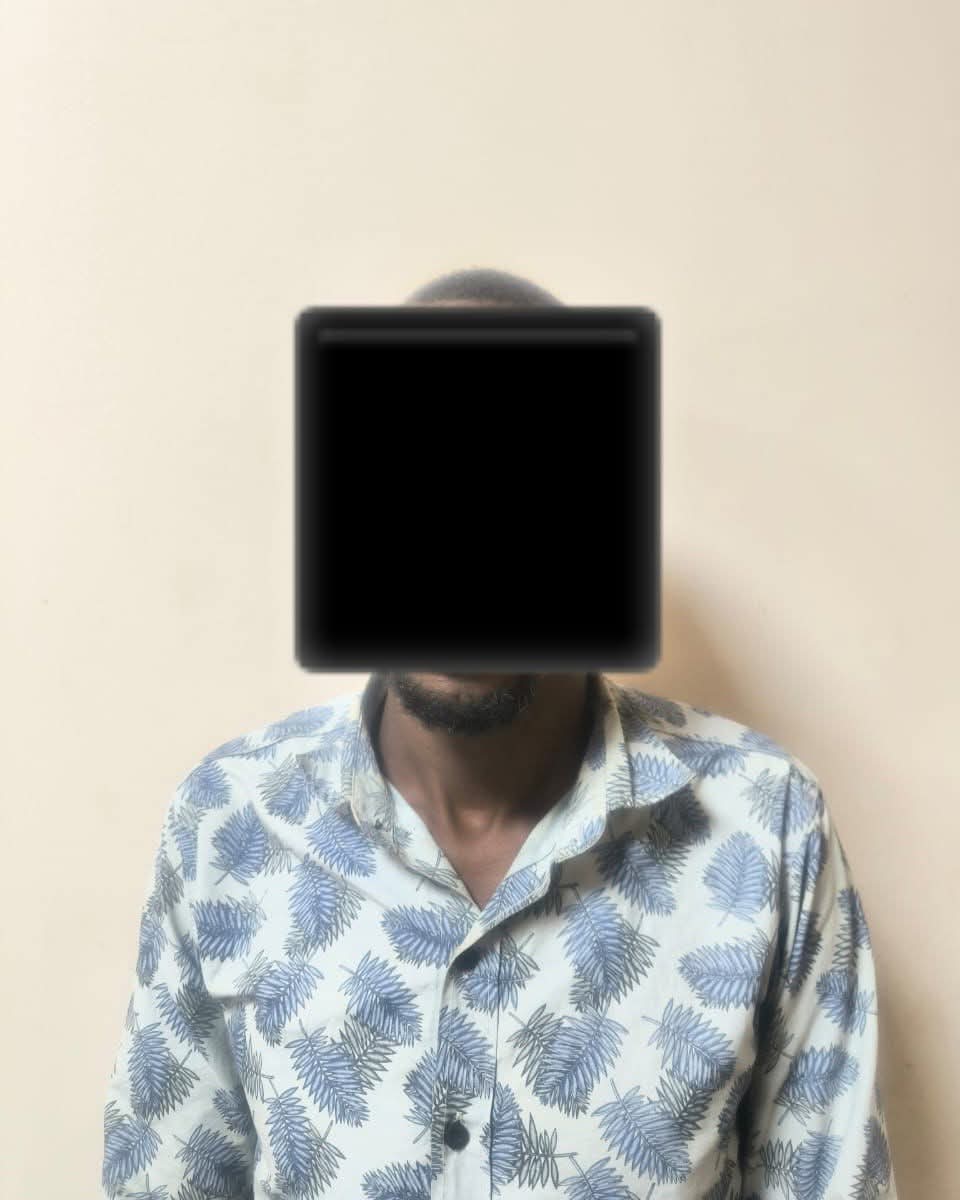 Person wearing a blue palm-leaf patterned shirt with their face obscured by a black square rectangle over the head and face area.