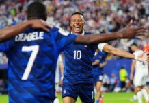 Mbappé Equals Klose’s World Cup Record as France Storm Into Knockout Stage Two soccer players in blue jerseys celebrate with arms open wide on a crowded field after a goal