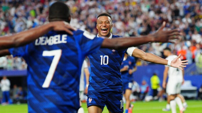 Two soccer players in blue jerseys celebrate with arms open wide on a crowded field after a goal