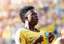 Brazil Cruise Past Scotland With Ruthless 3–0 Display Brazilian soccer player in a yellow jersey cheers on the field, pulling at his shirt in celebration.