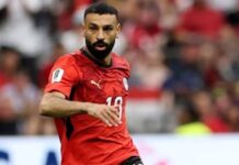 W’Cup: Egypt, Iran Share Entertaining Draw to Seal Knockout Qualification Soccer player in a red jersey with number 10, mid-action on the field during a match.