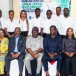 Oil And Gas Field Readiness: NCDMB, Chevron, Bristow Begin Pilot Training Group of professionals in business attire posing for a formal group photo in an office, with a Nigerian Content Human Capital Development banner in the background.