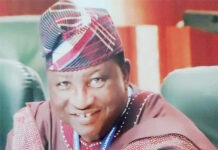 OPINION: Comrades Otunba Oladiti And Emeka Okafor: Leaders With Capacities Smiling man in traditional Nigerian attire with a patterned cap and maroon outfit, seated indoors with a blue lanyard visible.