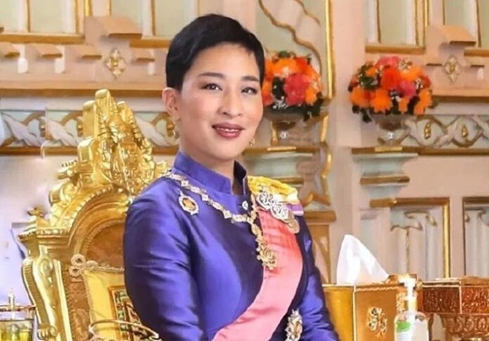 Woman in a royal purple dress with sash and ornate jewelry seated on a gilded throne.