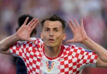 Budimir Fires Croatia Past Panama to Boost Knockout Hopes Croatian soccer player in a red-and-white checker kit celebrates with hands near his ears on the field.
