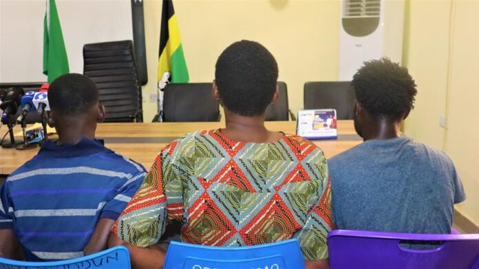 Sodeinde Olajuwon, Sakirudeen Abdulraheem Ayoola, and Sobu Obafunsho, Three people sit with their backs to the camera in a meeting room; microphones and flags are visible on the left side of a desk.