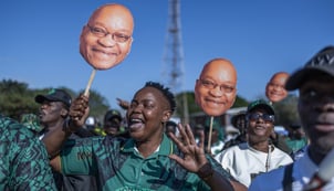 afp__20260610__b6ll8fr__v3__midres__topshotsafricaeconomydemo Crowd of supporters at an outdoor rally, holding oversized face cutouts of a smiling man and cheering.