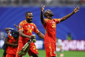image Two male soccer players in red uniforms celebrate on the field, with arms raised.