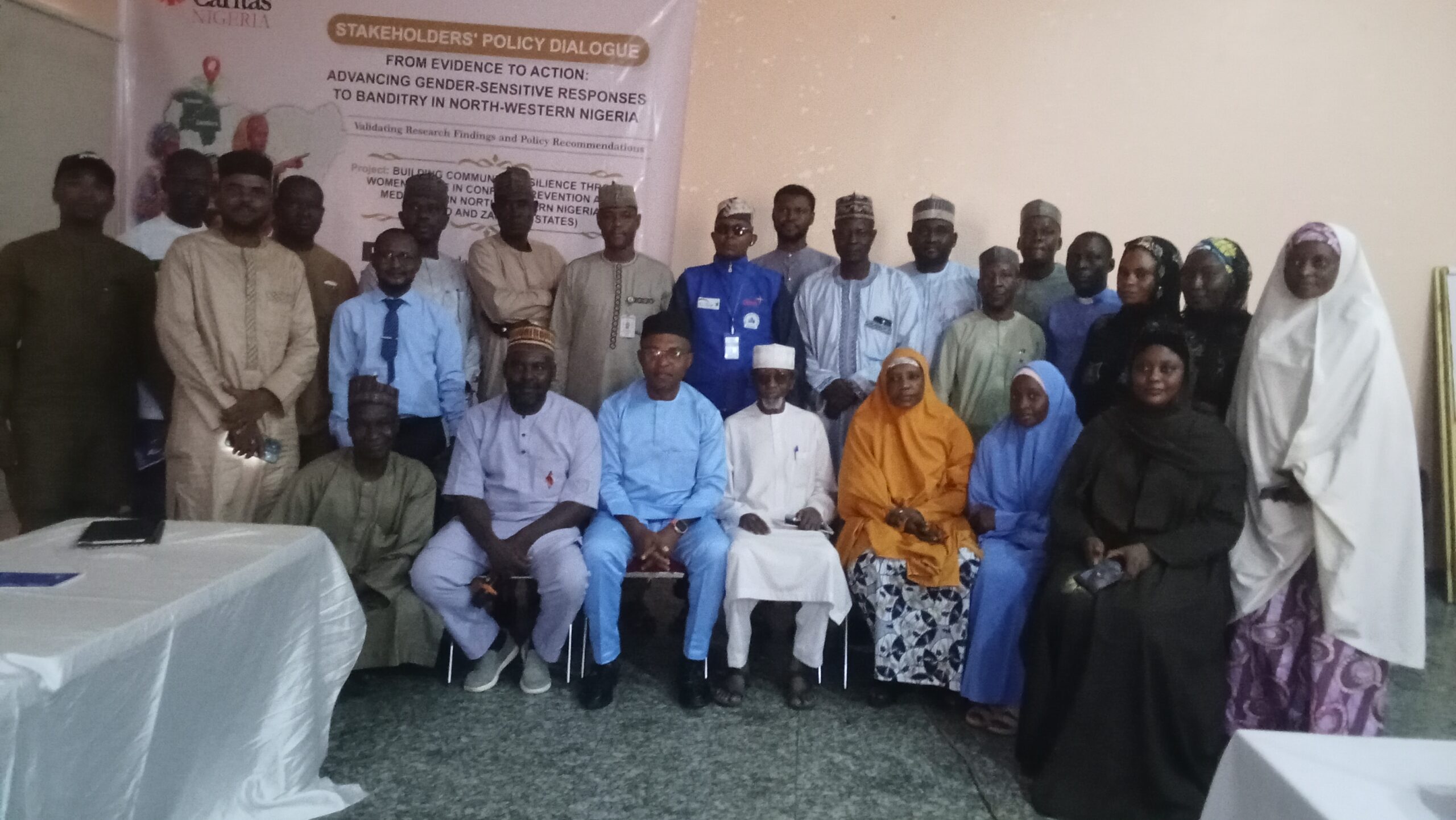 oplus_0 - THEWILL NEWS MEDIA Group of people posing for a photo at a stakeholders' policy dialogue event, with a banner in the background.